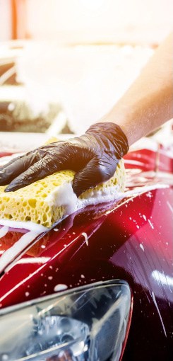 worker washing red car with sponge car wash